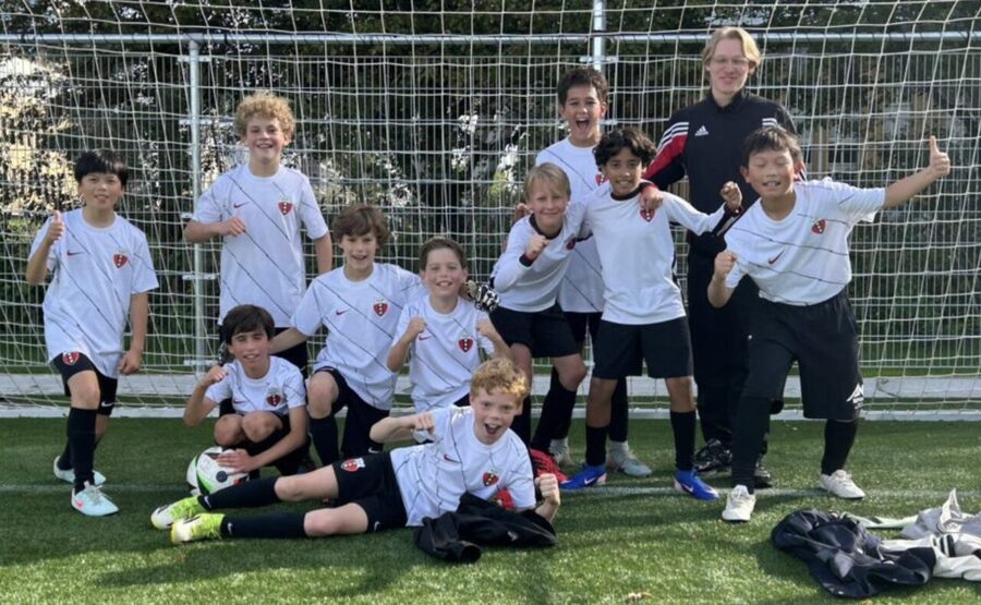 Spelers en trainer van RAP O12-1 juichen voor het doel na de promotie